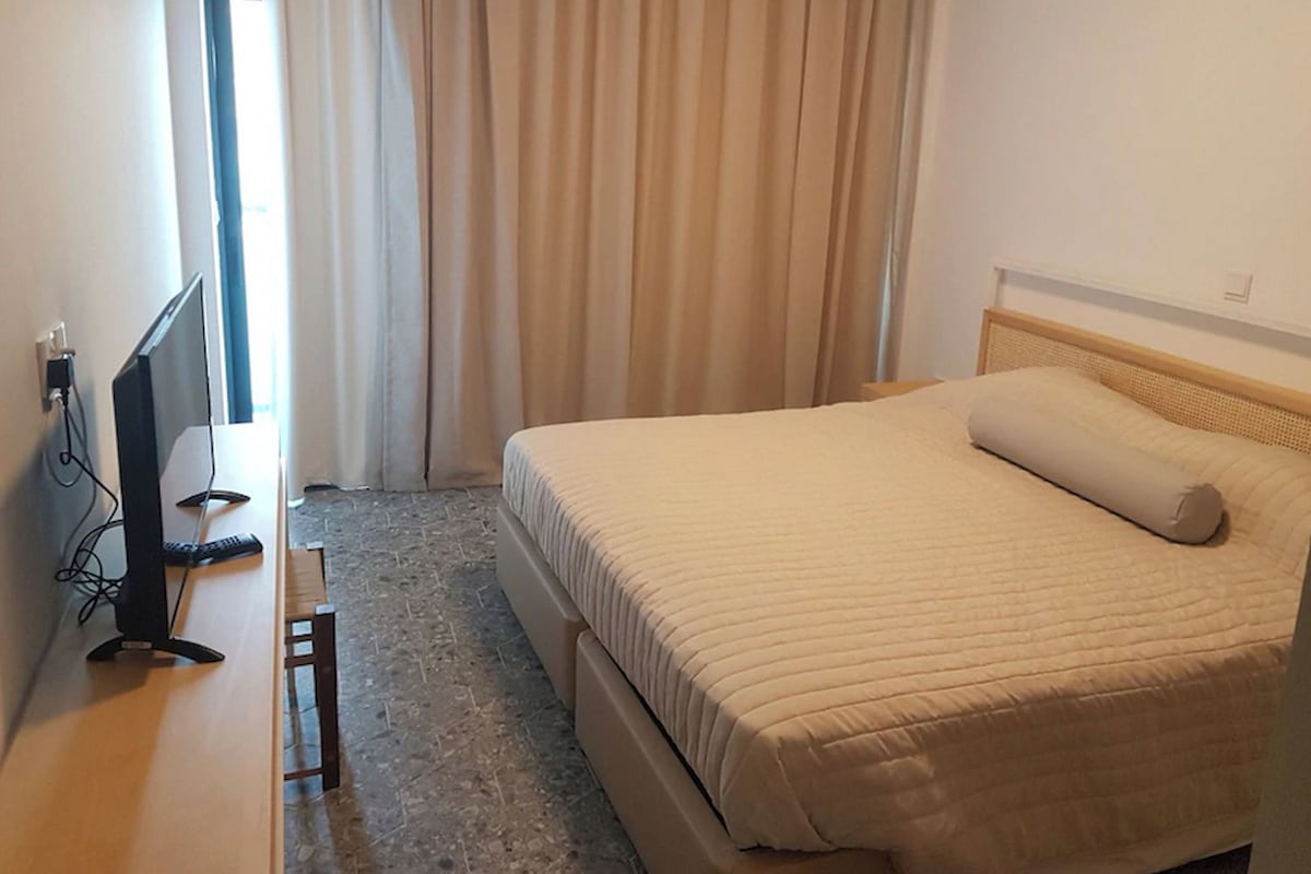 Una habitación de hotel con una cama, un escritorio con ordenador y una ventana con cortinas.