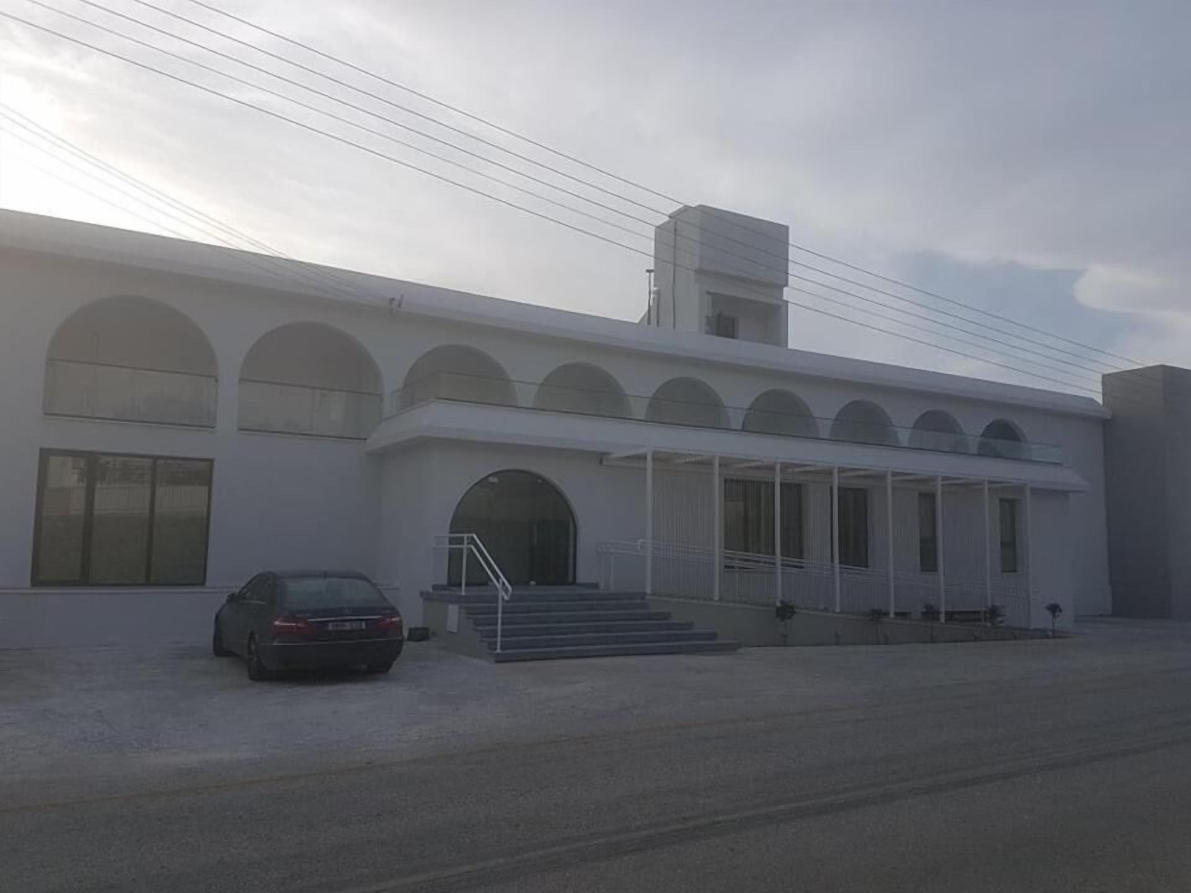 Un edificio moderno con fachada simétrica, amplios ventanales arqueados y una entrada central con escalones.