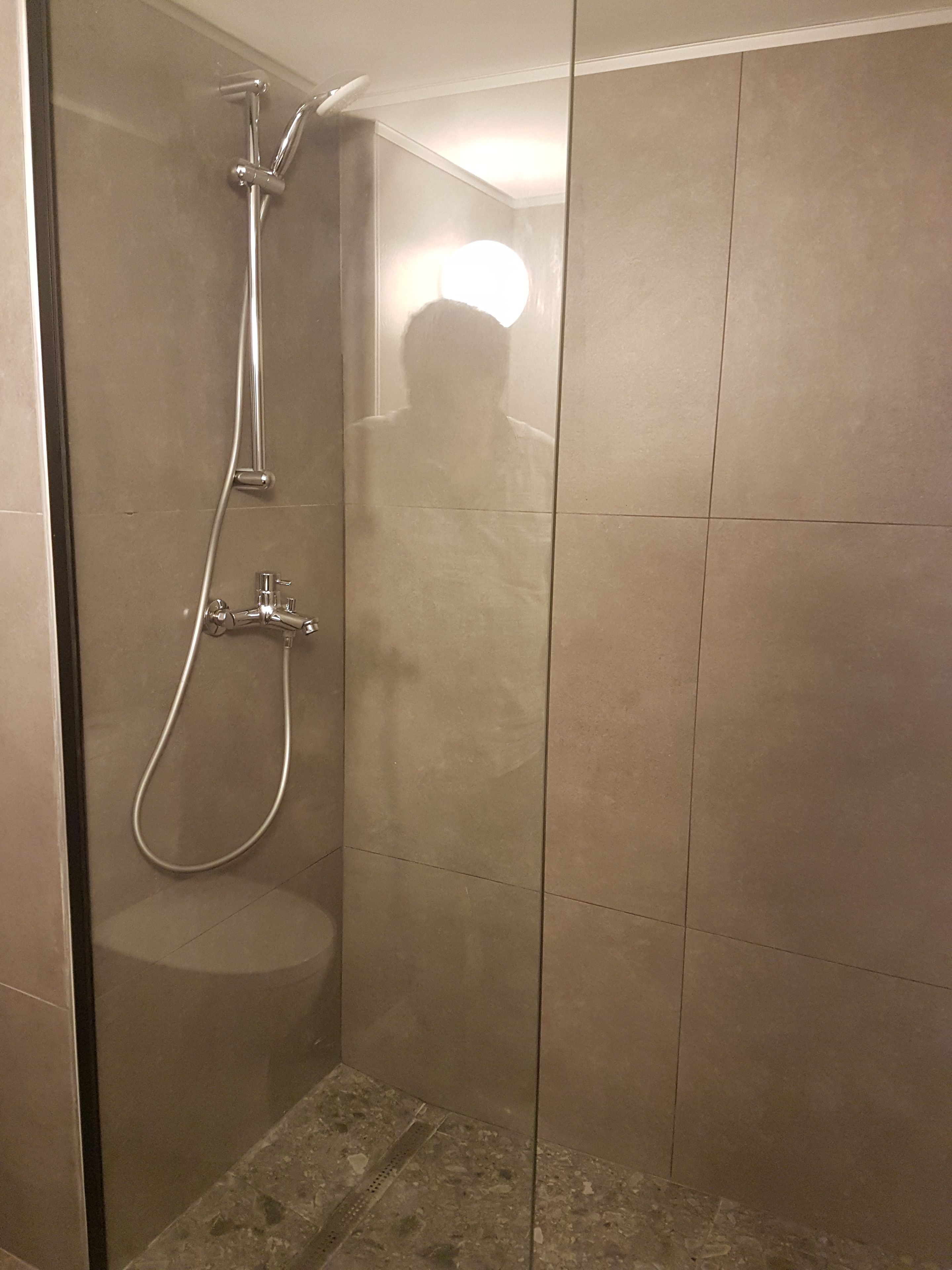 A shower with a handheld showerhead and a wall-mounted faucet.