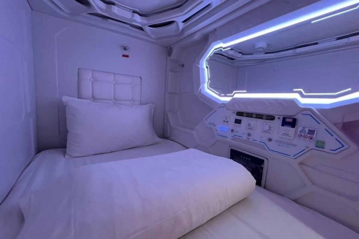 A futuristic room with a bed, control panels, and a geometric light design.