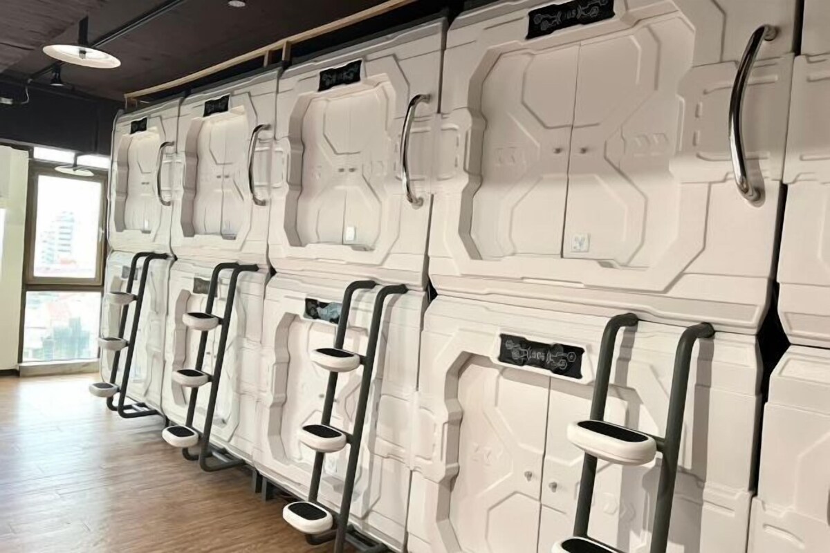 A row of white, futuristic-looking toilets with individual handrails and footrests, arranged in a modern bathroom setting.