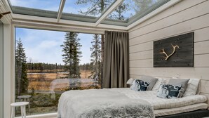 A bedroom with a large window, a bed with a white and black patterned blanket, and a wall-mounted artwork. - Iisakki Glass Village (Kuusamo)