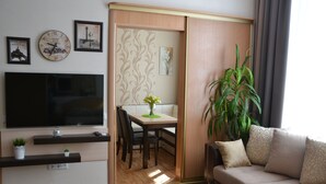 Un salon comprenant un téléviseur, une table à manger, des chaises, un canapé, une plante et une porte coulissante.