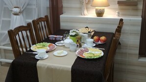 Une table à manger dressée avec des assiettes remplies de nourriture, une lampe et une petite statuette d’ange posée sur une étagère.