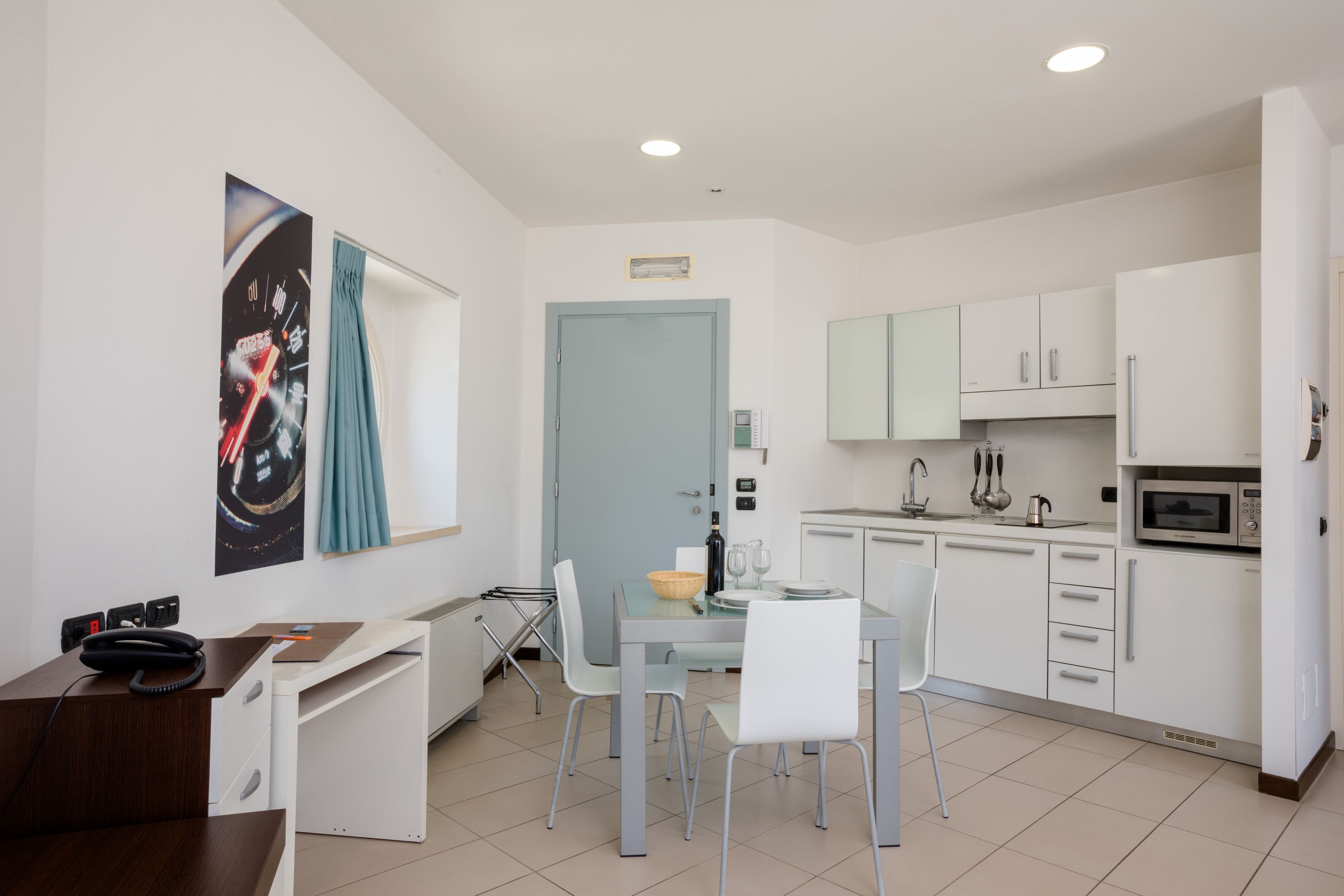 A modern kitchen with white cabinets, a microwave, and a dining area with a table and chairs.