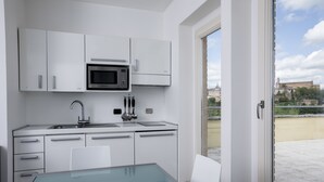 A modern kitchen with white cabinets, a stainless steel microwave, and a glass table.