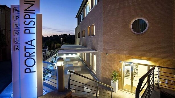 A modern building with a sign reading "PORTA PISPINI" and a staircase leading to an entrance.