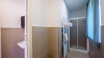 Ein Badezimmer mit Waschbecken, Handtuchhalter und einer Duschkabine mit Glastür.