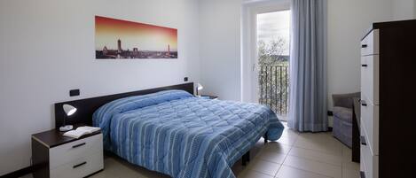 A bedroom with a bed, nightstand, dresser, and a cityscape painting on the wall.