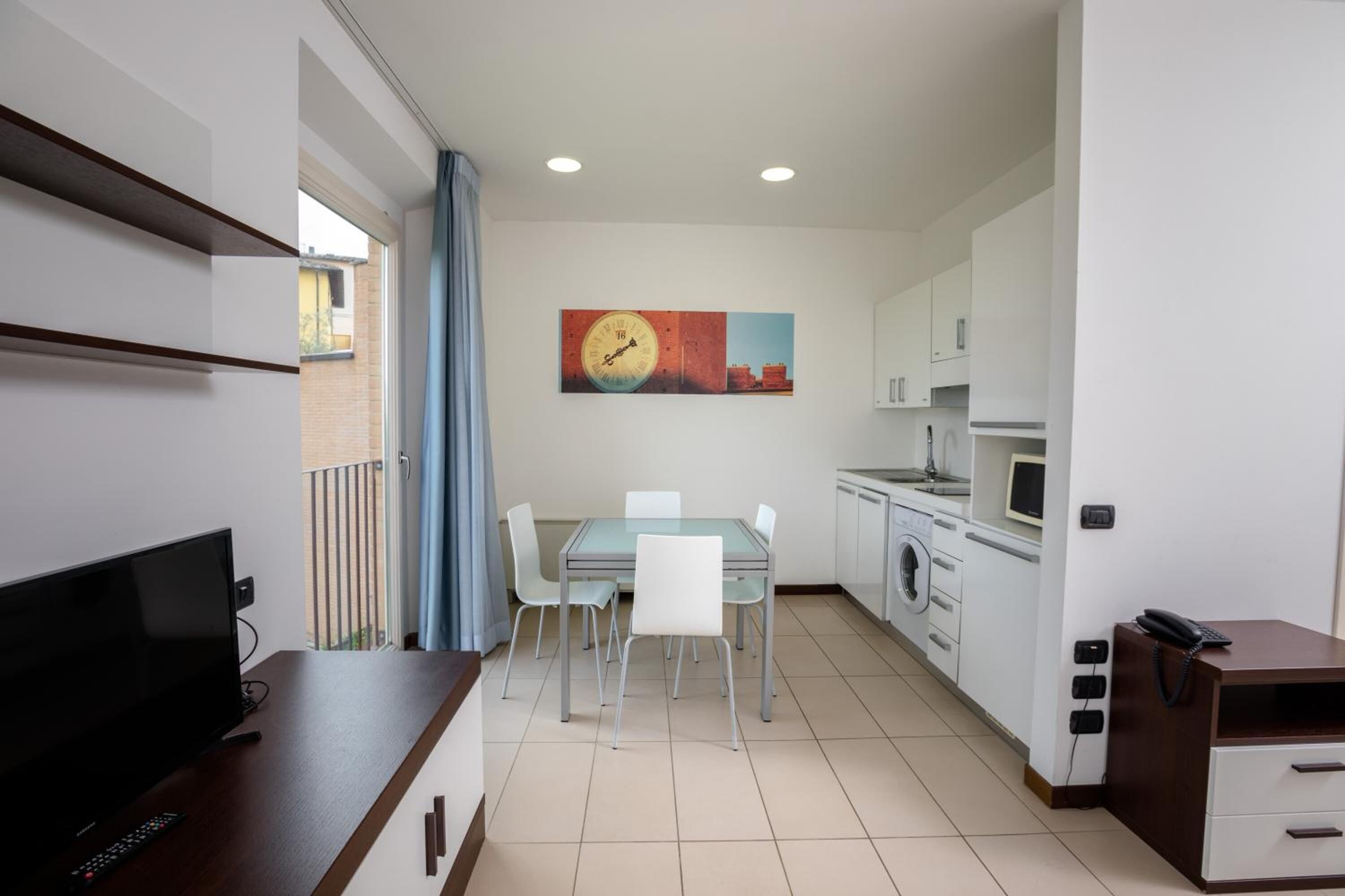 A compact living space with a dining area, kitchenette, and a TV on a wooden table.
