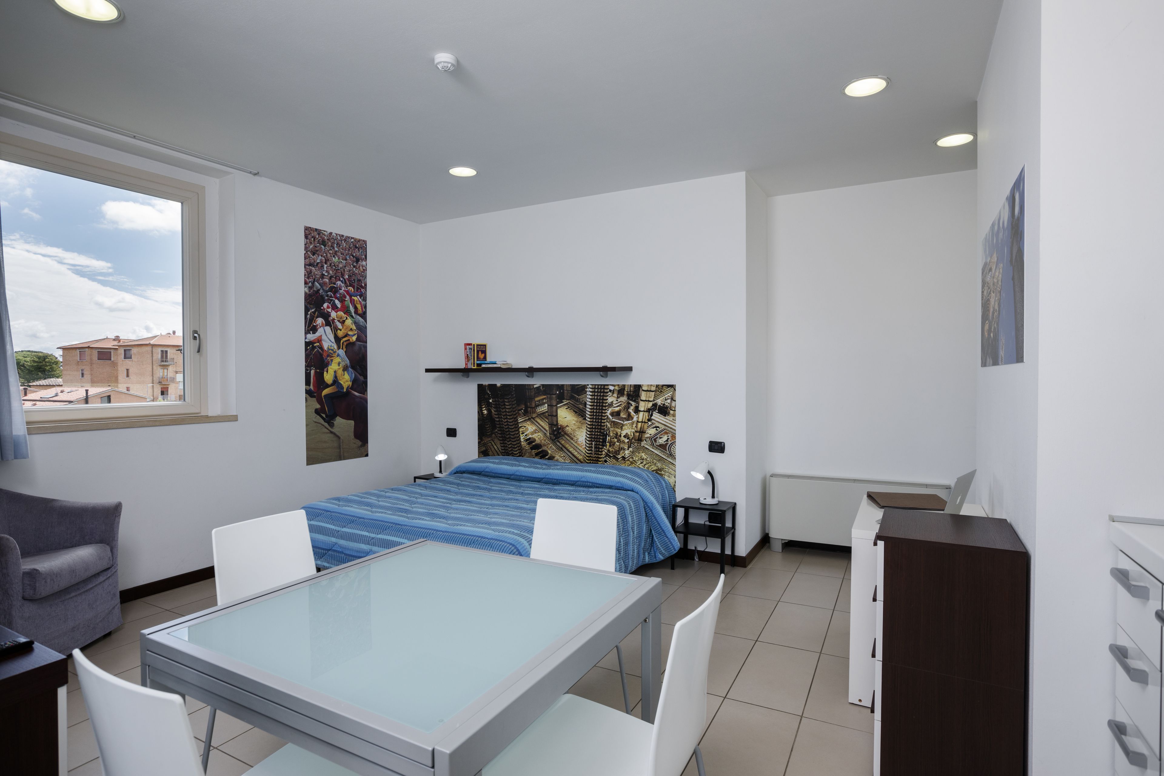 Een moderne hotelkamer met een bed, een bureau, een stoel, een tafel en een raam.