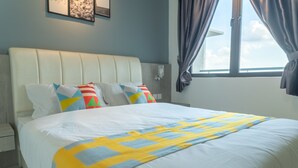 A neatly made bed with a white headboard and colorful pillows, a window with curtains, and a light blue wall.