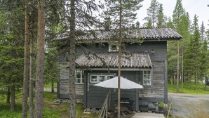 A rustic cabin with a wooden deck, a covered outdoor seating area, and a small porch.