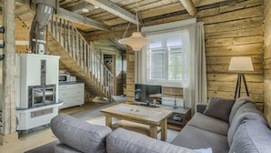 A cozy log cabin interior with a living room, sofa, TV, and a staircase.