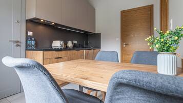 A modern kitchen with a wooden table and grey upholstered chairs.