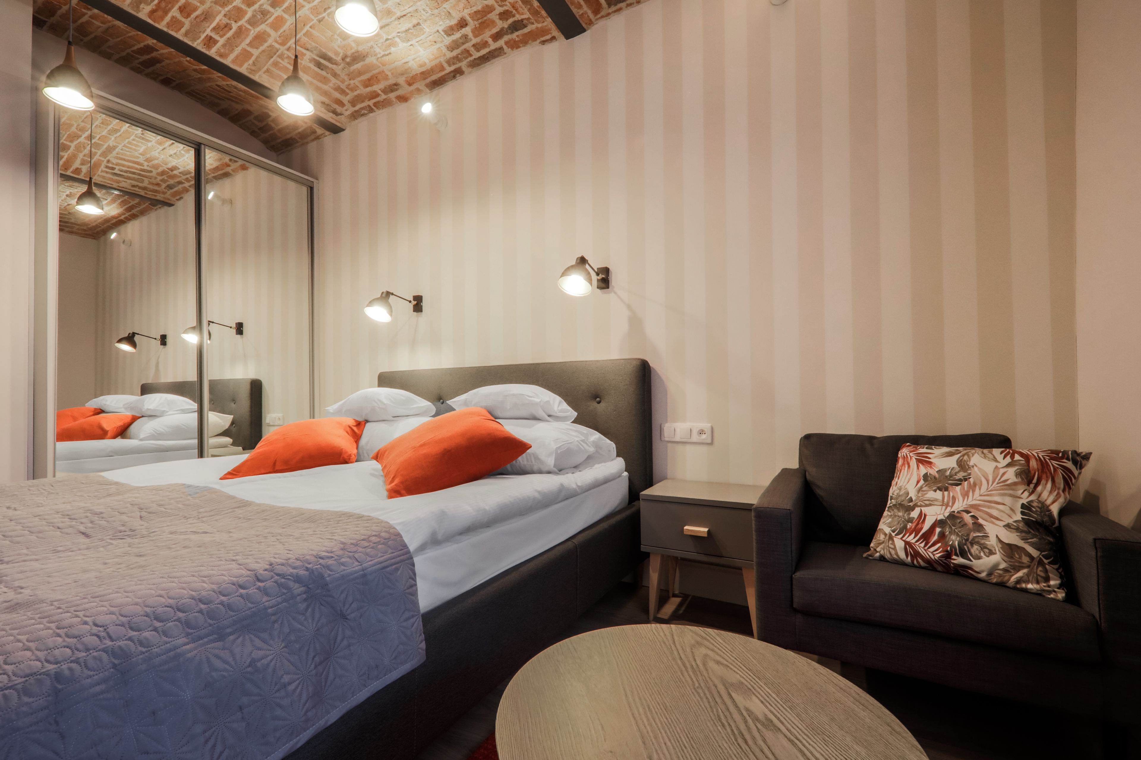 Une chambre à coucher avec un lit, un canapé, une table de chevet et un miroir.