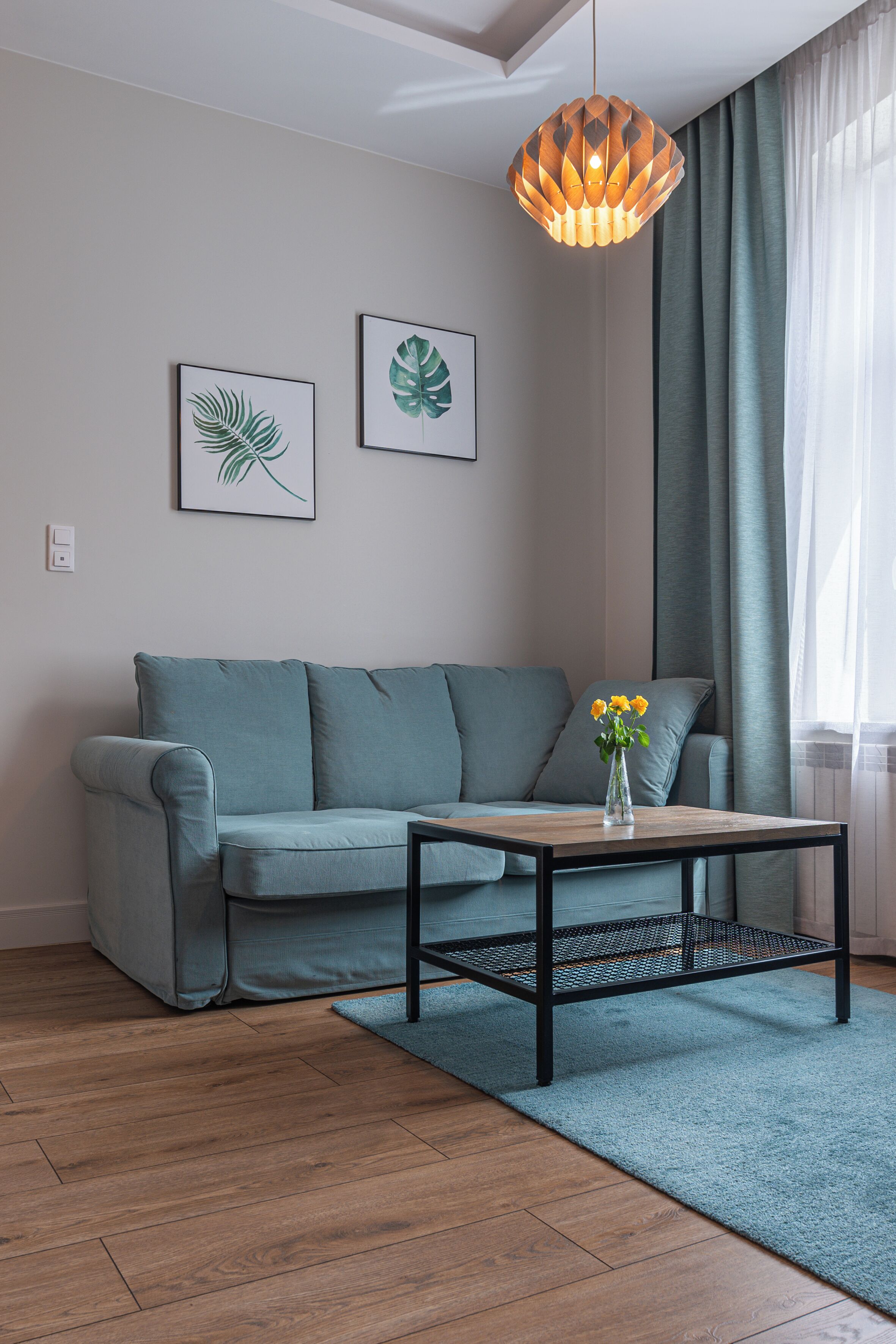 A modern living room with a grey sofa, a wooden coffee table, and a hanging pendant light.