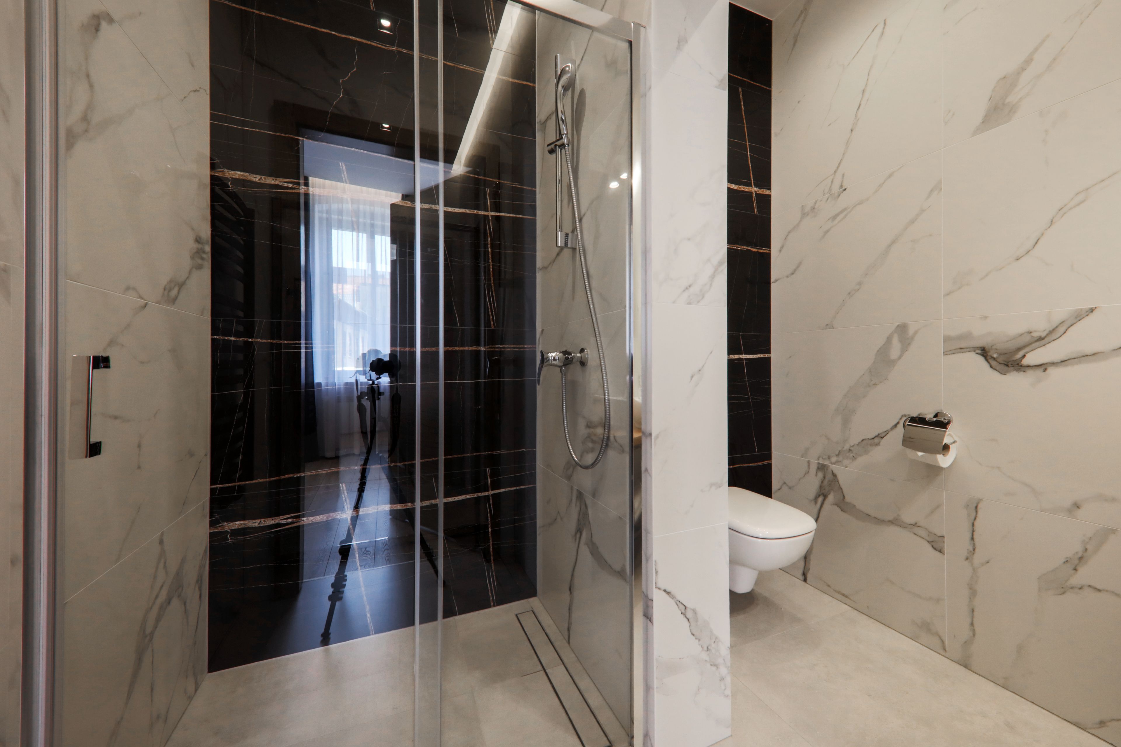 Un baño moderno con cabina de ducha de vidrio, inodoro y paredes de mármol.