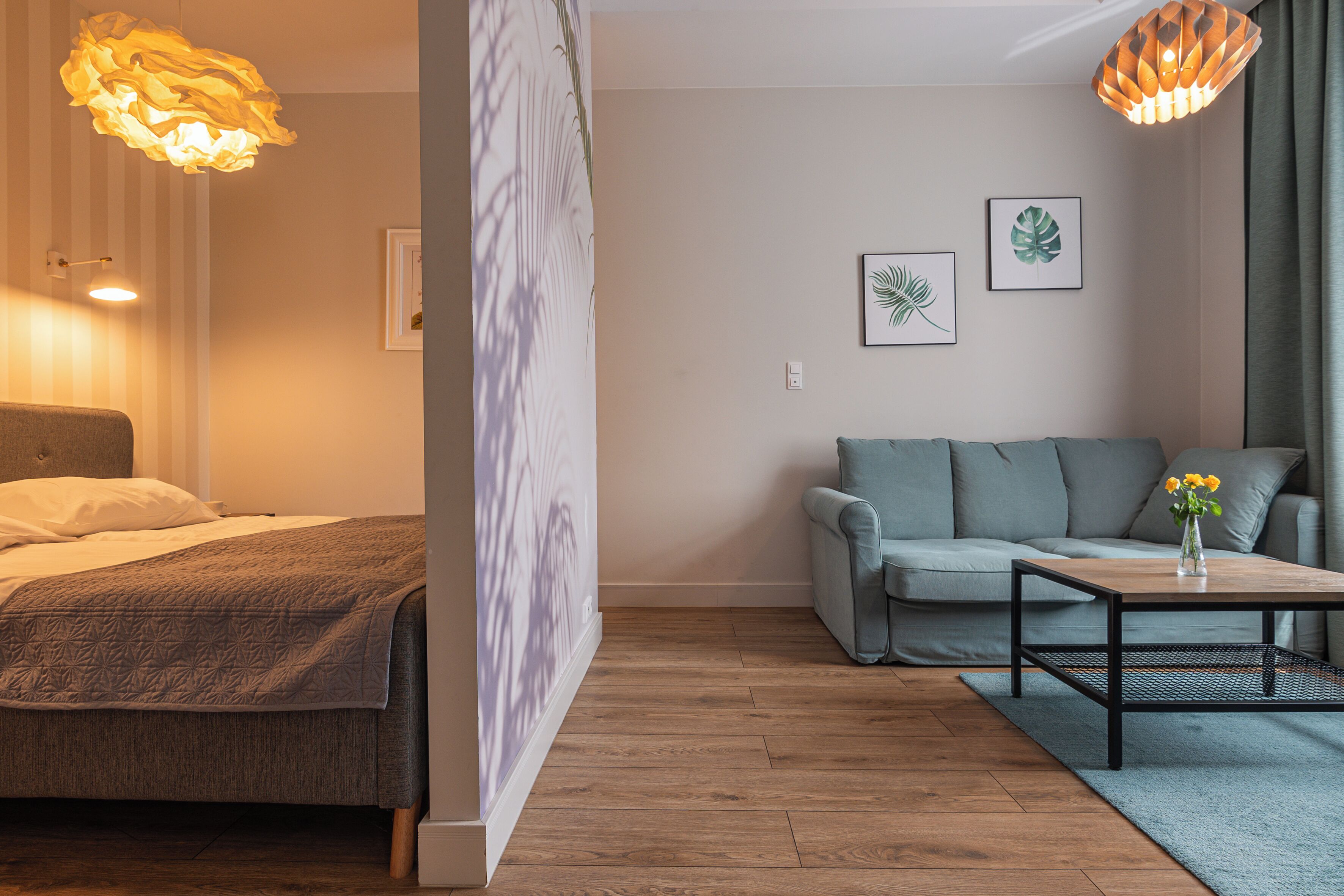 Ein modernes Schlafzimmer mit einem Bett, einem grauen Sofa, einem Holztisch und zwei Wandleuchten.