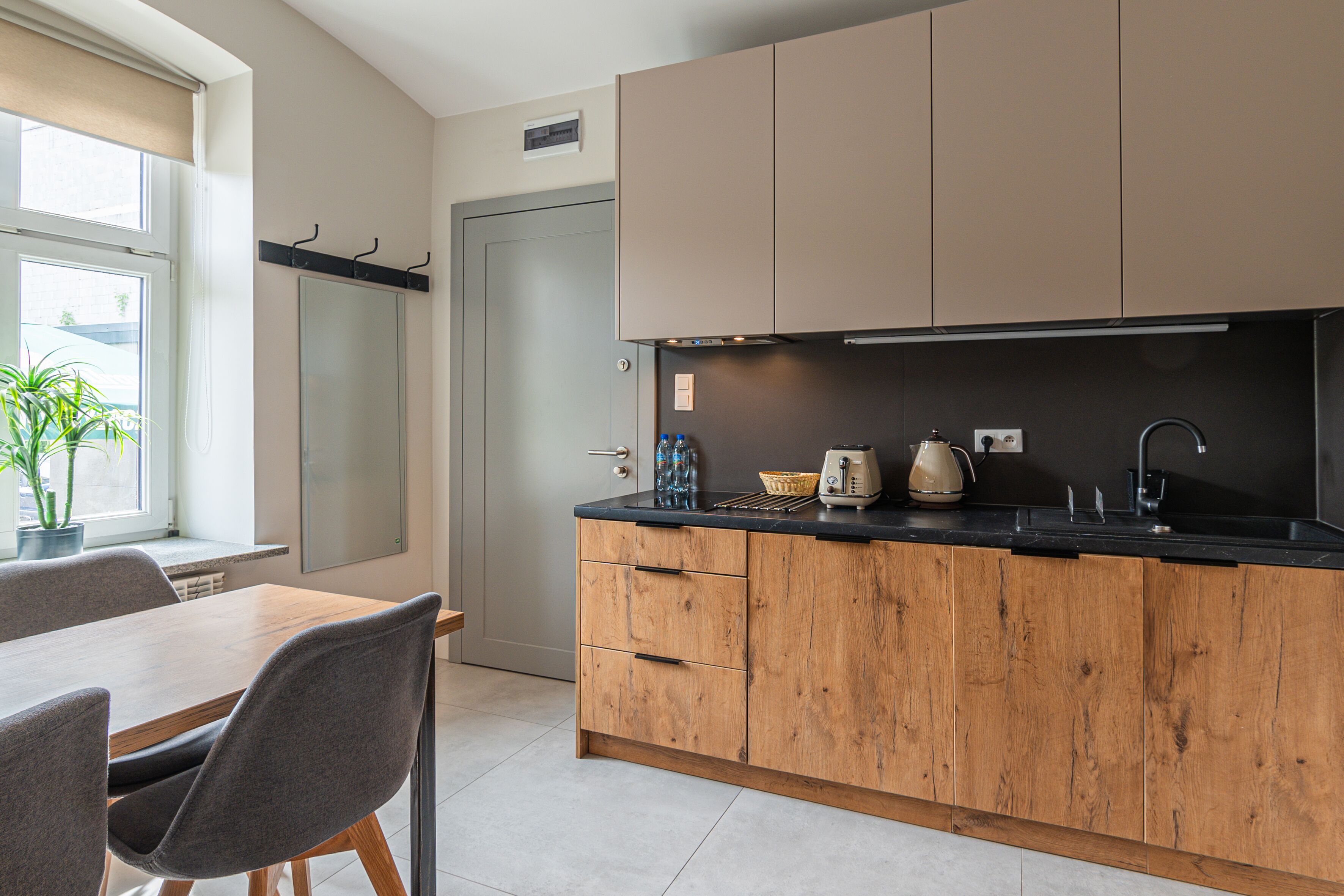 Una cocina moderna con armarios de madera, una encimera negra y una zona de comedor con mesa y sillas.