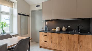 Una cocina moderna con armarios de madera, una encimera negra y una zona de comedor con mesa y sillas.