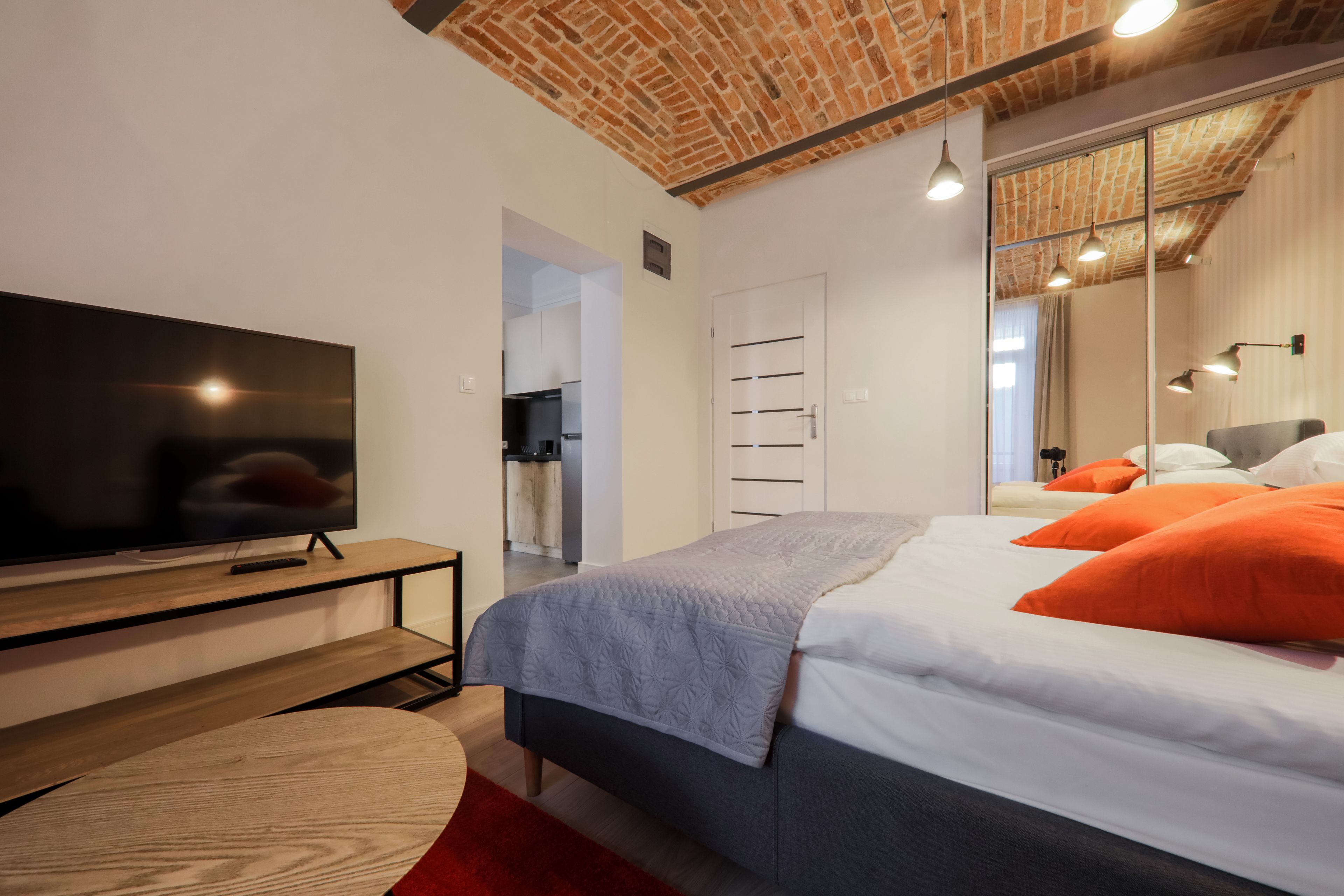Un dormitorio moderno con televisión, cama y espejo.