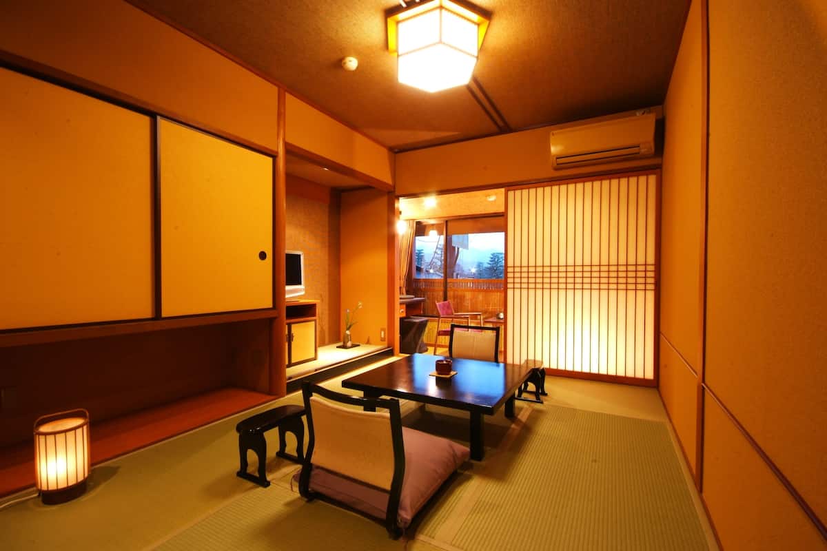 A traditional Japanese room with tatami flooring, a low table with cushions, and sliding doors.