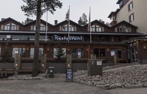 A restaurant with a wooden facade, outdoor seating, and a sign indicating it is open. - Zone Apartments (Kuusamo)