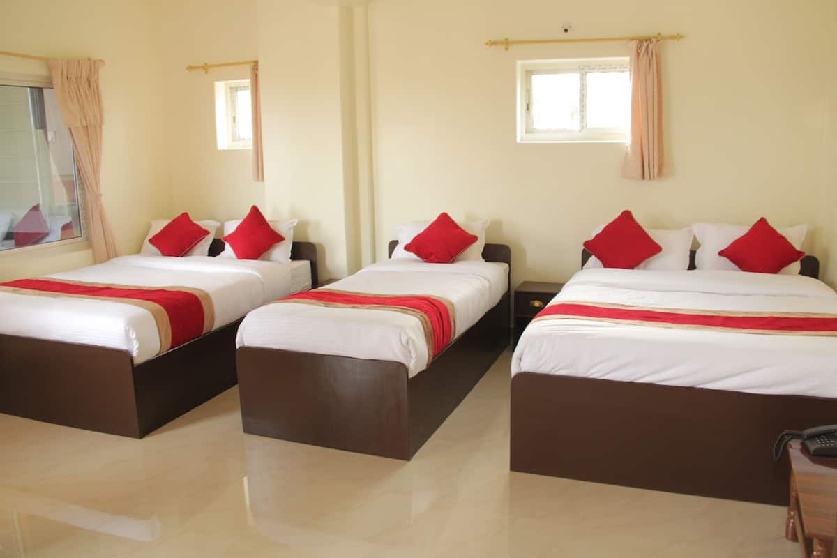 Quarto de hotel com três camas, cada uma com roupa de cama vermelha e branca, e cabeceira de madeira.