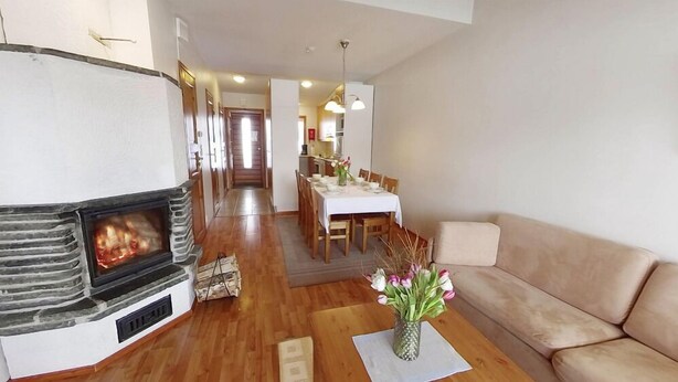 Una sala de estar con chimenea, un comedor con mesa y sillas, y un sofá.