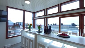 A modern kitchen with large windows, a white countertop, and a view of the city. - Hotel Arctic Zone (Kuusamo)