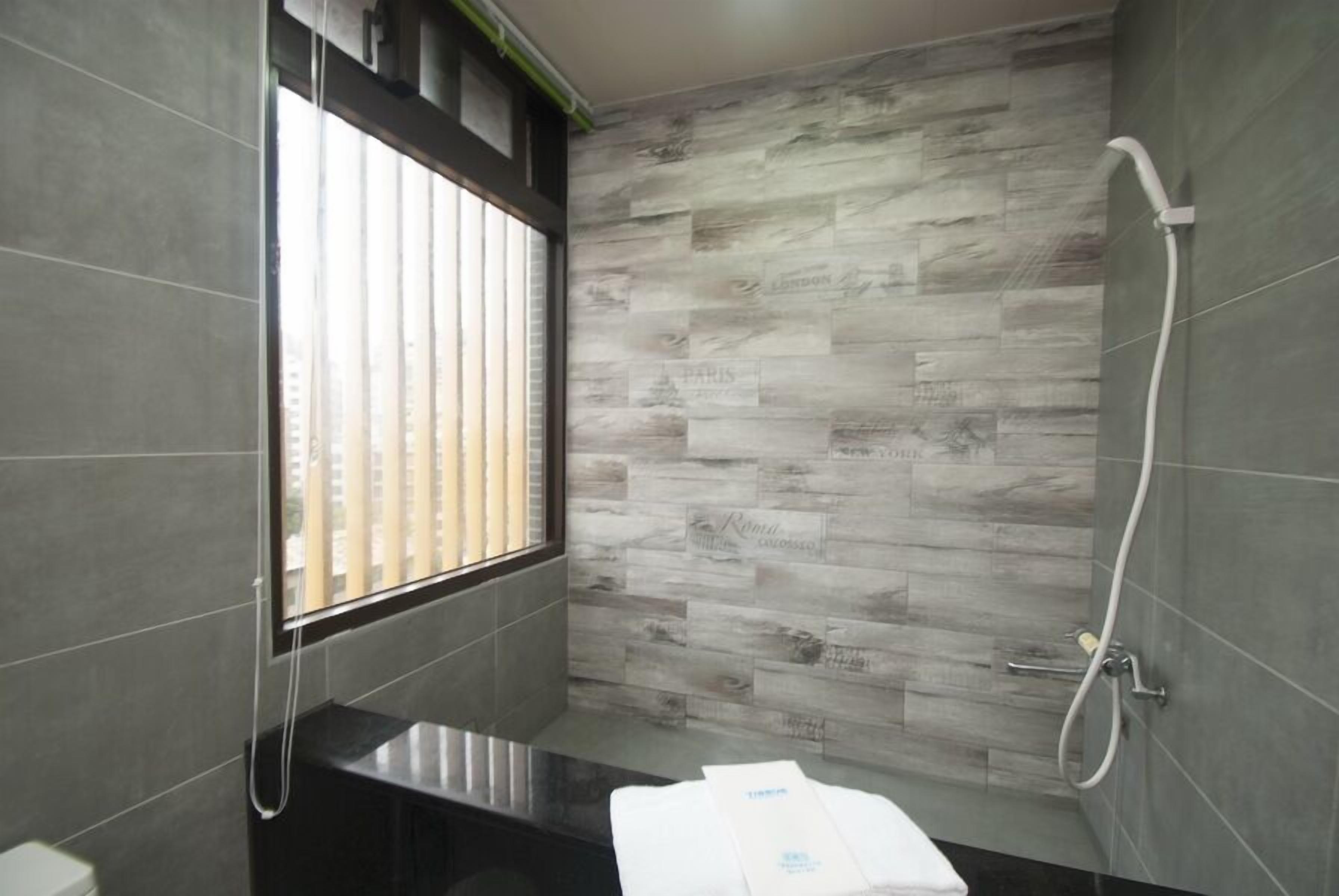 Une salle de bain moderne équipée d’une douche, de toilettes et d’une fenêtre avec stores.