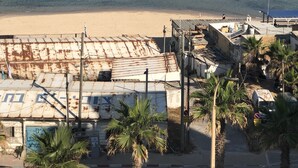 Une plage avec un rivage rocheux, une plage de sable et des bâtiments dont les toits sont rouillés.