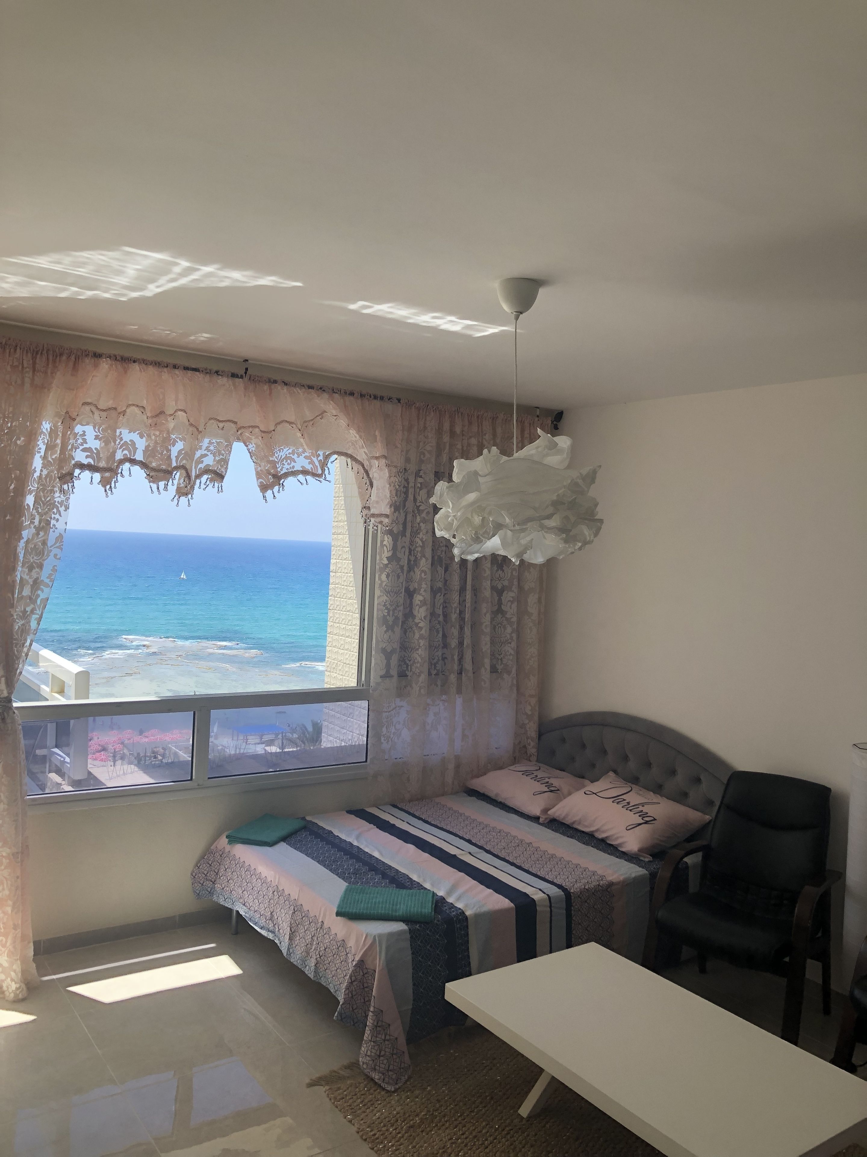 Een slaapkamer met een bed, een stoel, een tafel en uitzicht op zee.