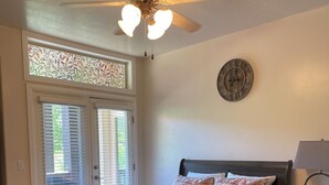 A bedroom with a bed, a ceiling fan, a clock, and a window with blinds. - Perfect destination for summer fun and winter sports! (Huntsville)