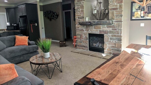 A living room with a stone fireplace, a dining table, and a sofa. - Perfect destination for summer fun and winter sports! (Huntsville)