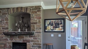 A stone fireplace with a mantel, a chandelier, and a framed artwork above it. - Perfect destination for summer fun and winter sports! (Huntsville)