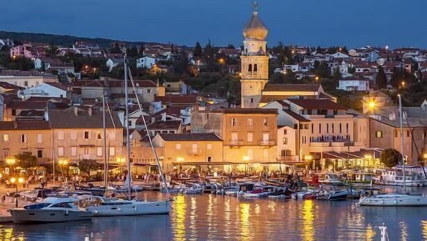 Marina con barcos, piscina y edificios que incluyen una torre destacada.