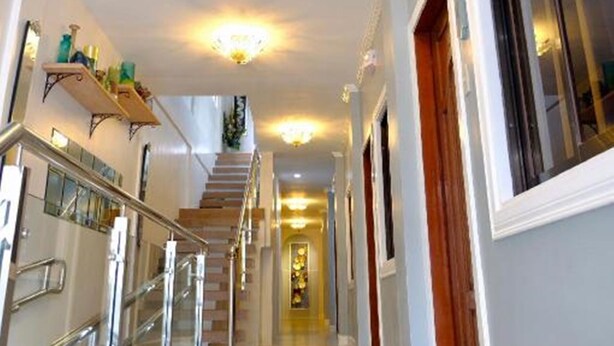 A spacious hallway with a staircase, a chandelier, and a balcony with plants. - Blue Waters Inn Coron (Coron)