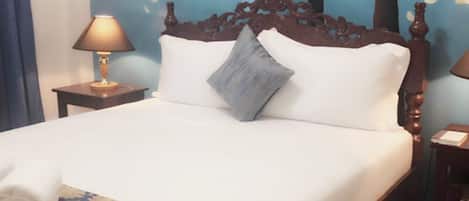 Een net opgemaakt bed met een bedsprei met patroon, een houten hoofdbord en een muurschildering van kersenbloesems.
