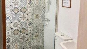 A bathroom with a patterned tile wall, a glass shower enclosure, a toilet, and a sink.