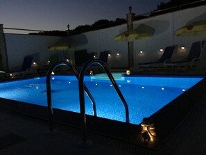 Una piscina al aire libre de temporada, sombrillas