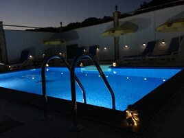 Una piscina al aire libre de temporada, sombrillas