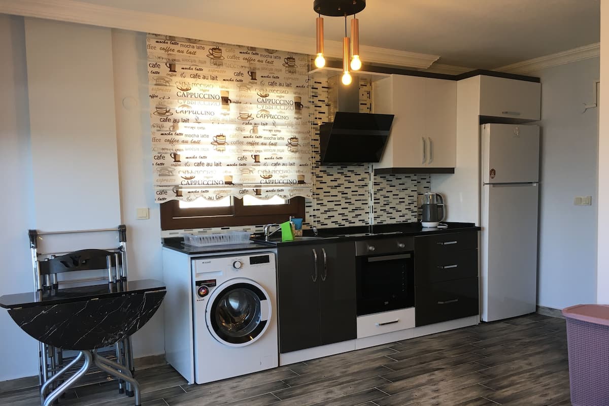 A compact kitchen with a washing machine, a sink, a coffee machine, and a refrigerator.