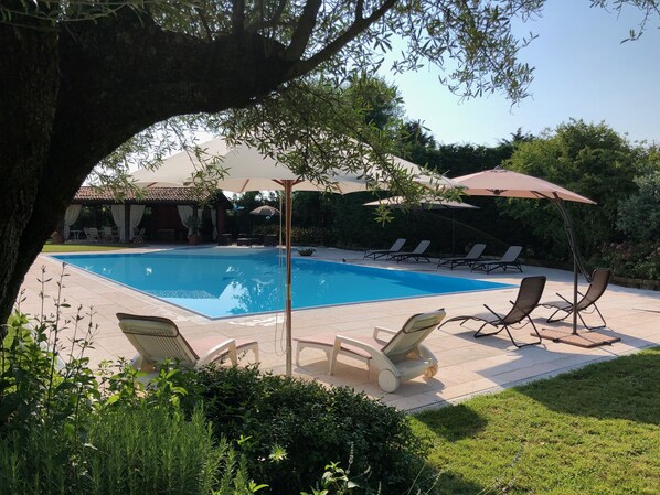 Una piscina al aire libre de temporada, sombrillas