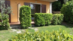 A house with a well-maintained garden, a stone pathway, and a door leading to the entrance. - Villa Girasole B&B (Torri del Benaco)