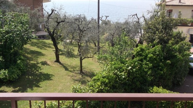 A residential area with a grassy lawn, trees, and houses with a view of the sea. - Villa Girasole B&B (Torri del Benaco)