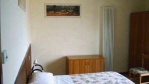 A bedroom with a bed, a wooden cabinet, a radiator, and a chair. - Villa Girasole B&B (Torri del Benaco)