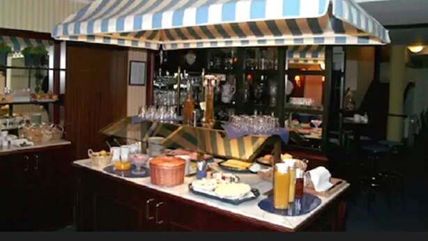 A buffet setup with a striped canopy, a bar area with glasses and bottles, and various food items on the counter. - Hotel Buchholz (Berlin)