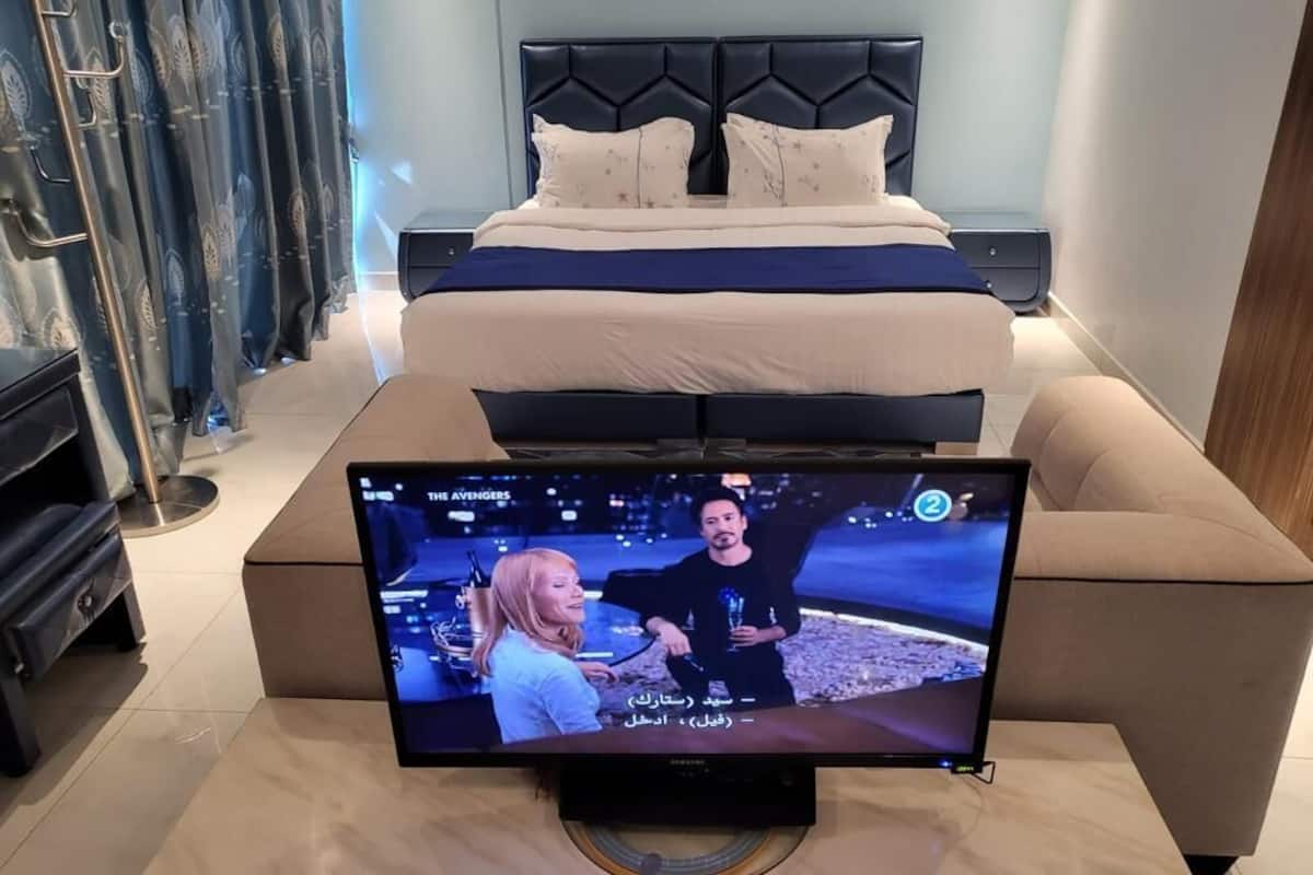 A bedroom with a bed, a television on a stand, and a nightstand.
